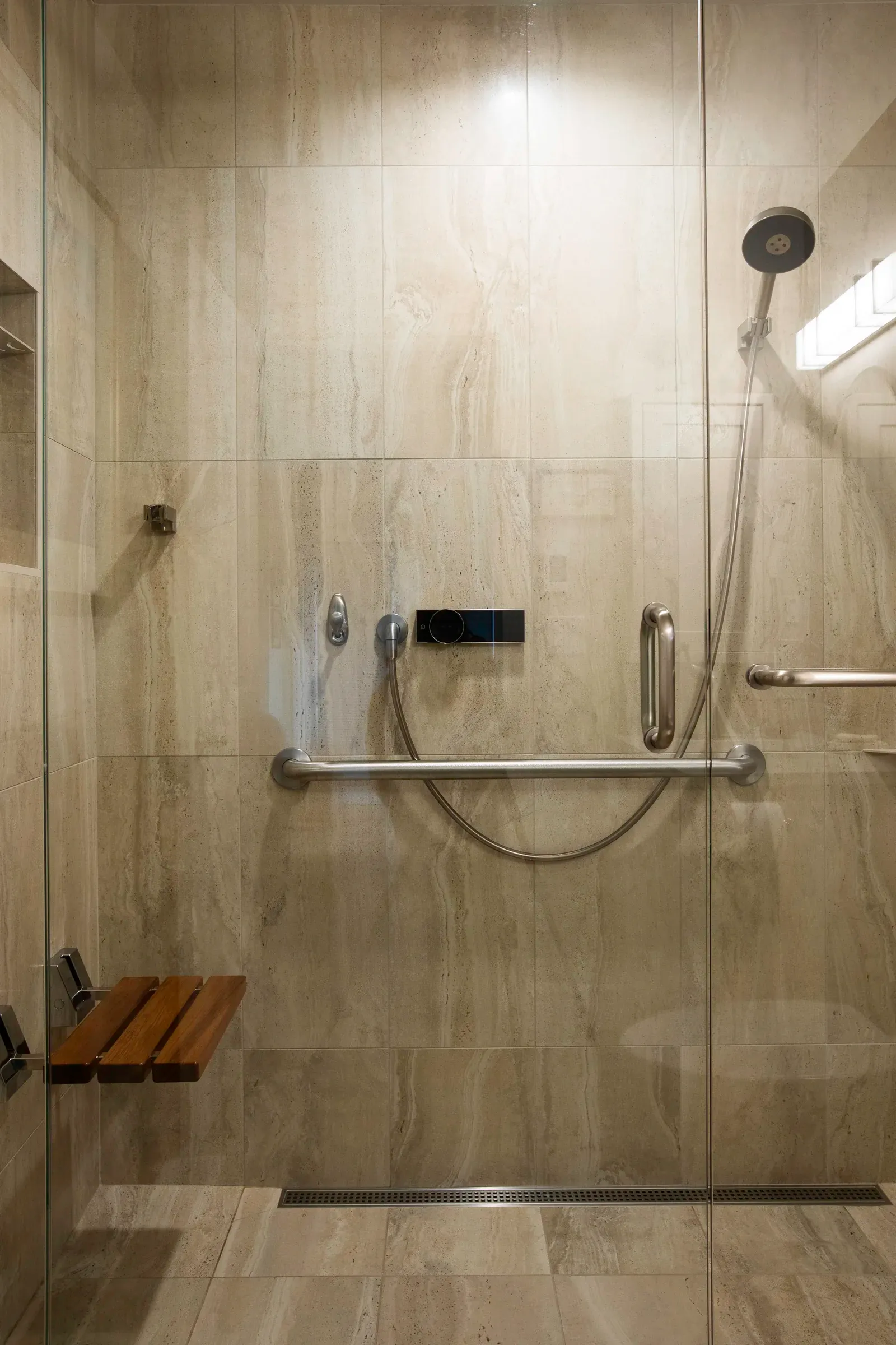 Walk-in shower lined with softly veined stone tile